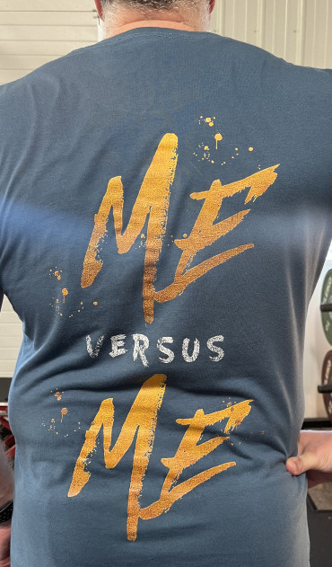 Picture of my back with a blue shirt on that has "Me versus Me" screenprinted on it.